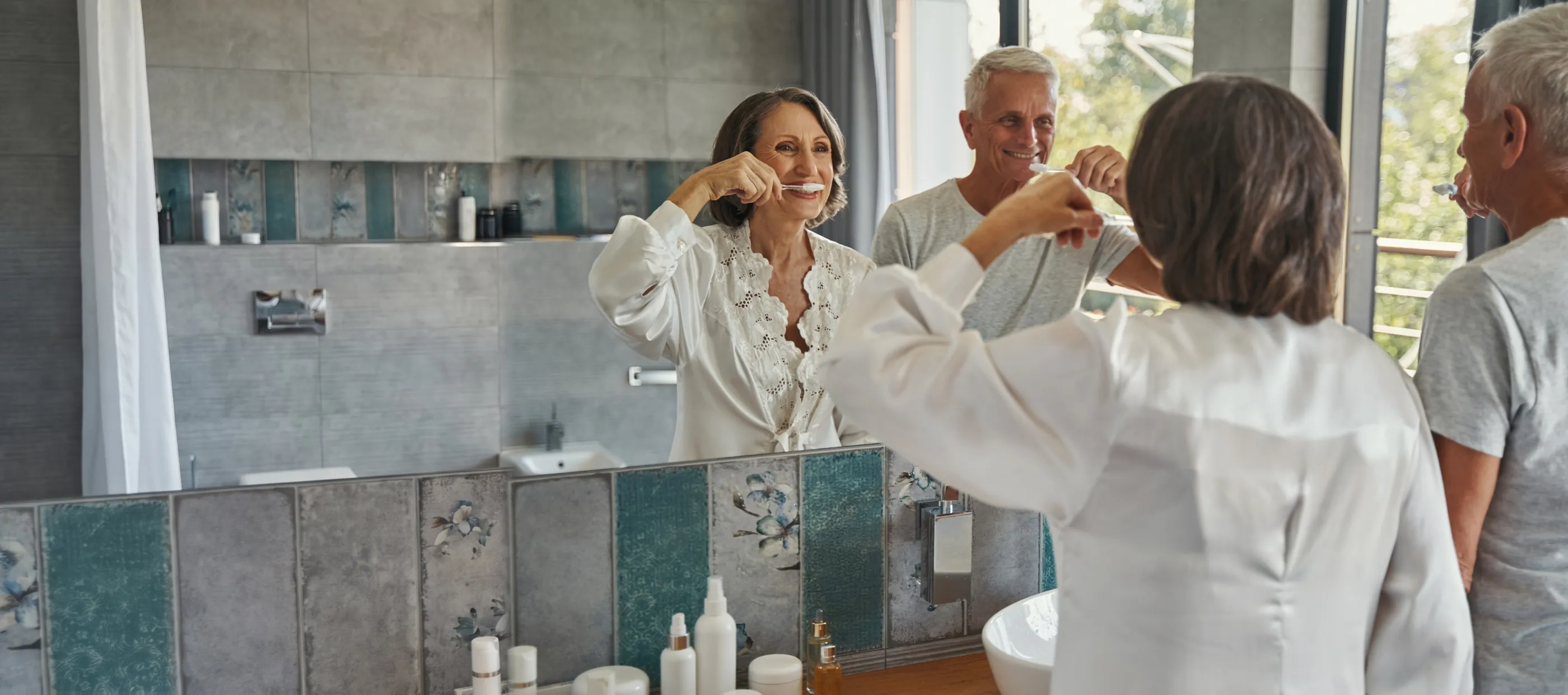 A couple brushing their teeth together at the bathroom mirror
