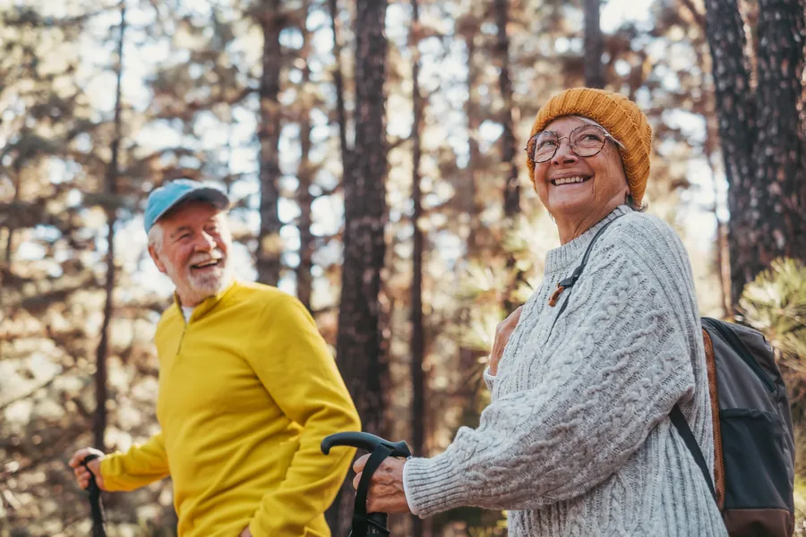 An older couple out walking among the trees, smiling