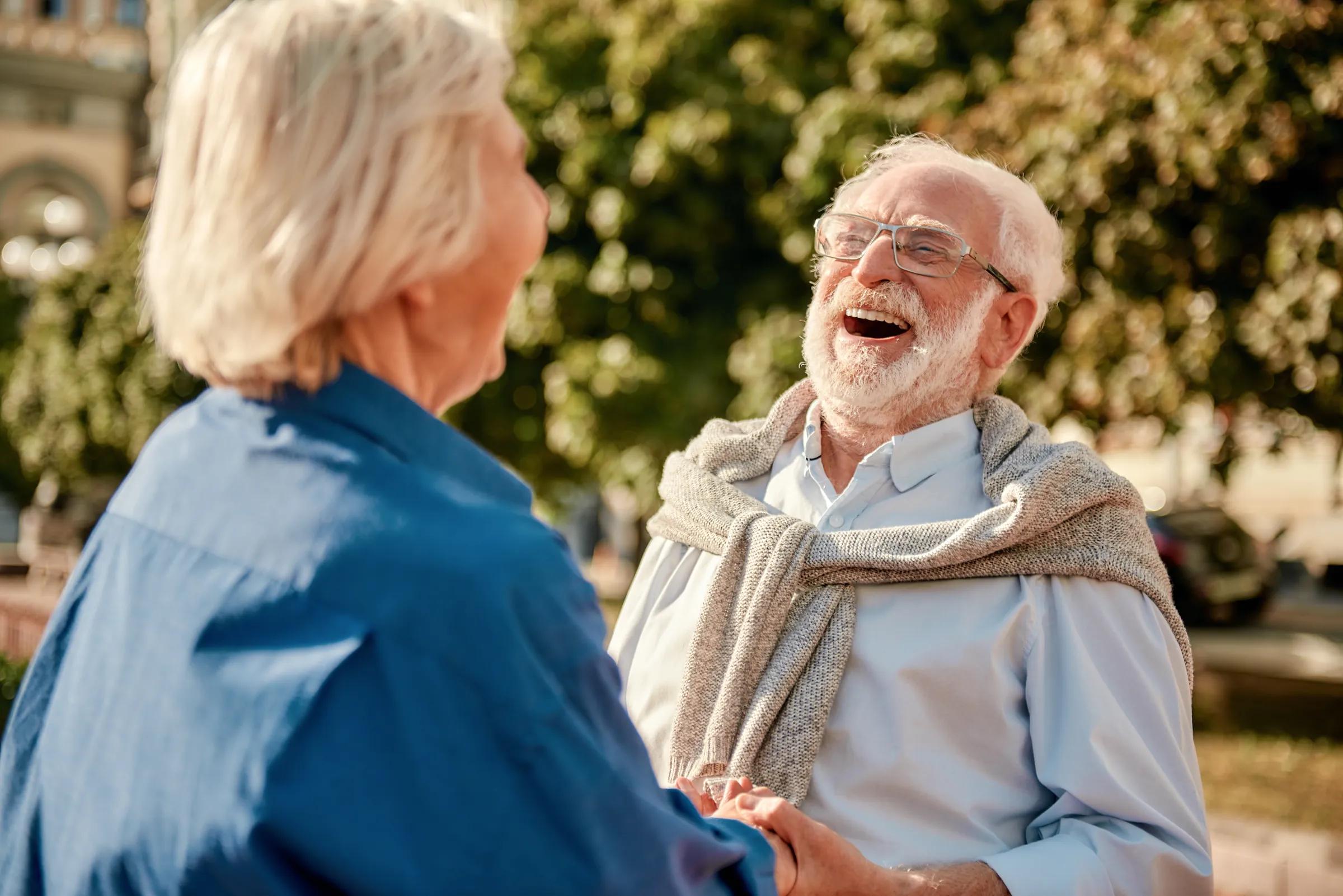 A couple holding hands and laughing outdoors