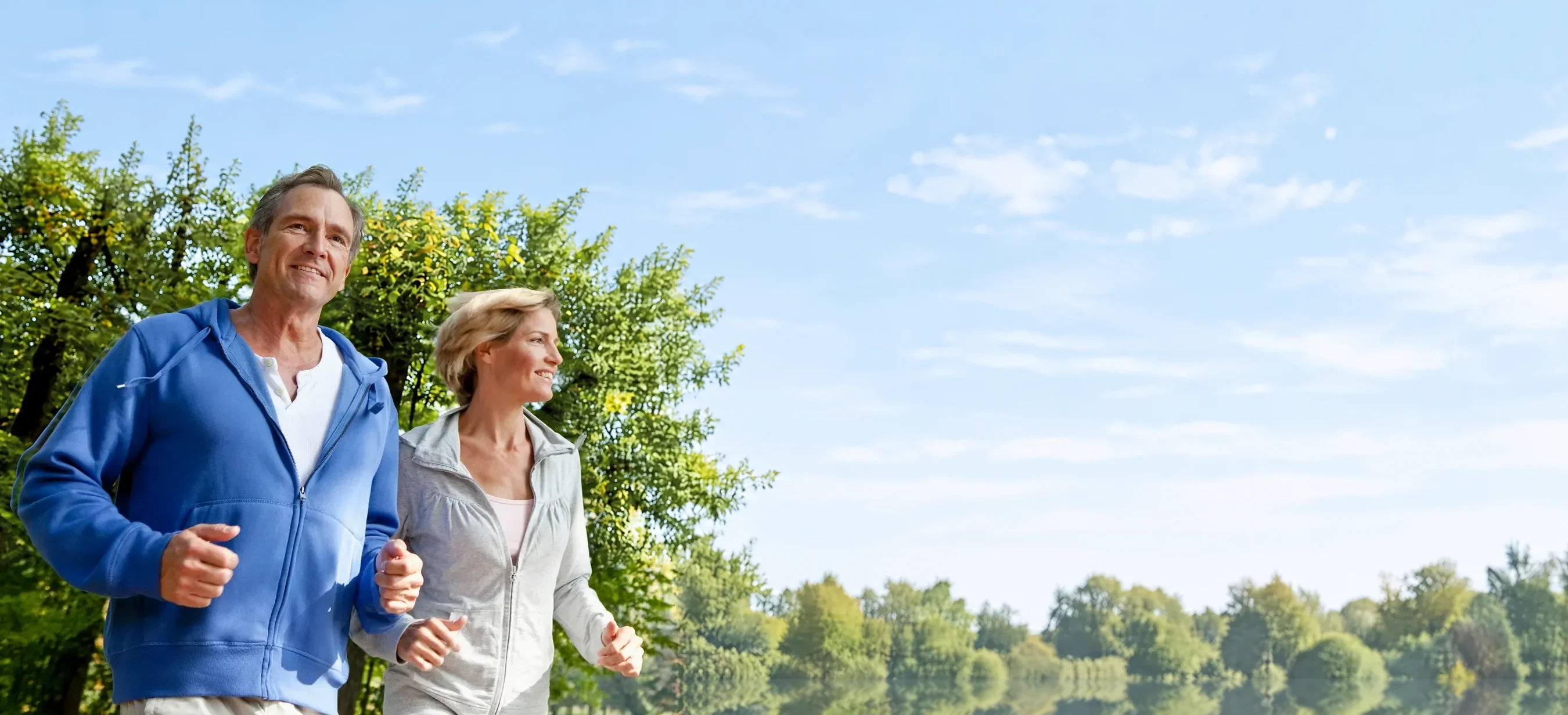 A couple jogging together under the trees