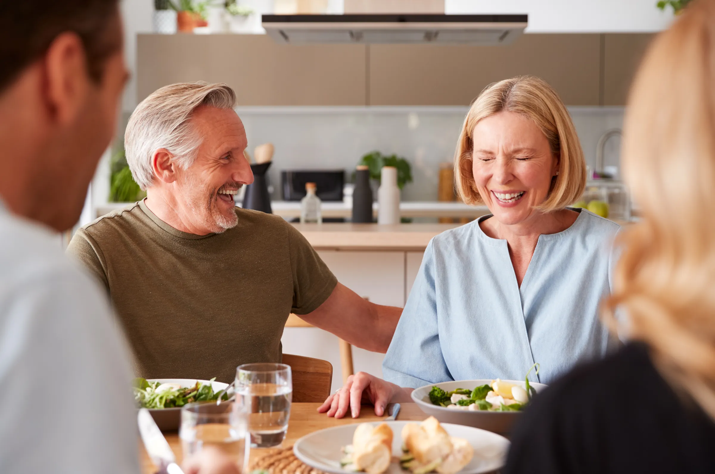 An older couple laughing together at their kitchen table