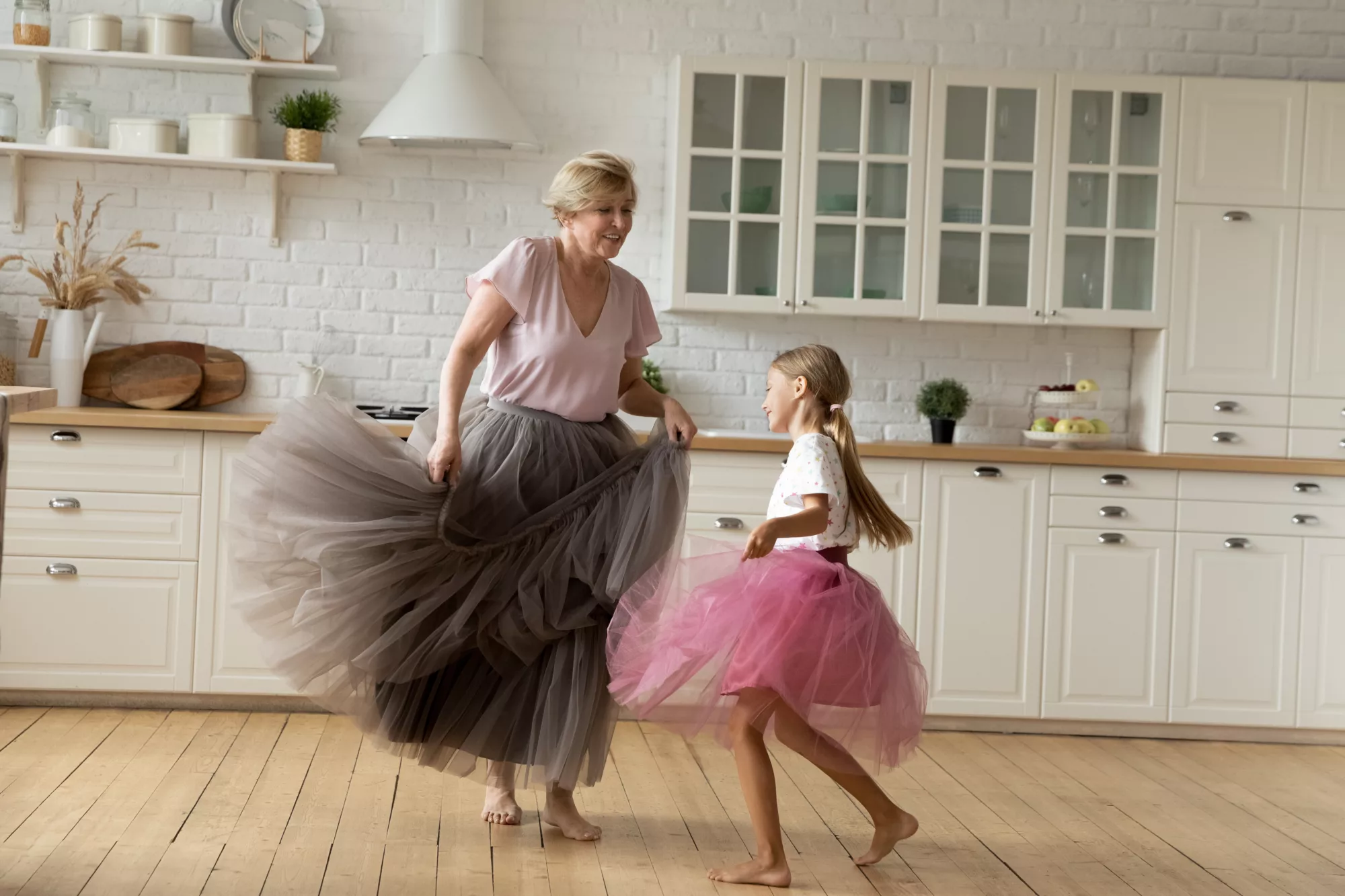 A grandmother and her granddaughter dancing in tutus